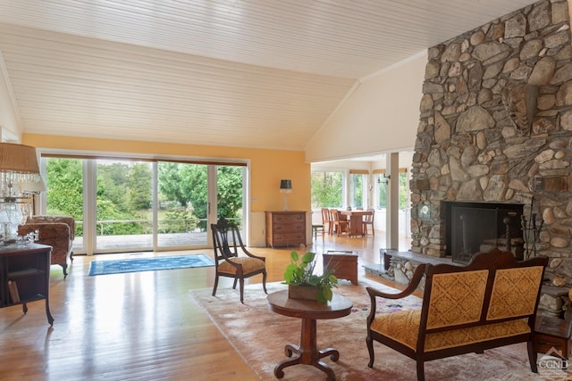 living room featuring a healthy amount of sunlight, a stone fireplace, wooden ceiling, and light hardwood / wood-style flooring