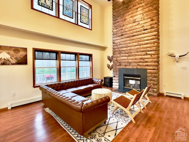 living room with a stone fireplace, a baseboard radiator, and wood-type flooring