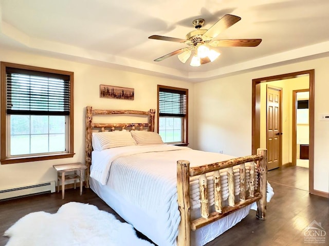 bedroom with baseboard heating, multiple windows, ceiling fan, and dark wood-type flooring