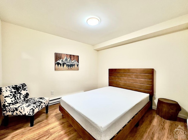 bedroom featuring hardwood / wood-style flooring and a baseboard heating unit