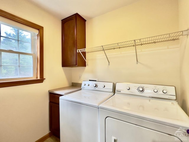 clothes washing area with washer and dryer and cabinets