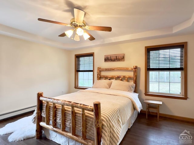 bedroom with dark hardwood / wood-style floors, baseboard heating, and ceiling fan