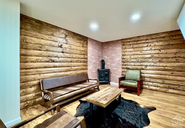 sitting room featuring wood-type flooring, rustic walls, and a wood stove