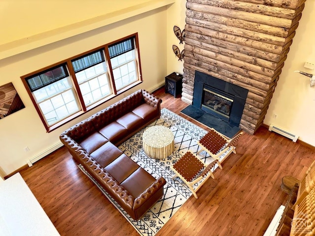 living room featuring a stone fireplace, dark wood-type flooring, and a baseboard radiator