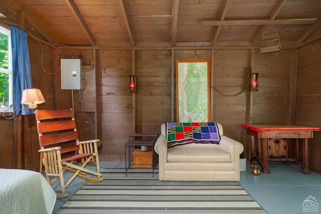 interior space featuring electric panel, wooden walls, concrete floors, and lofted ceiling