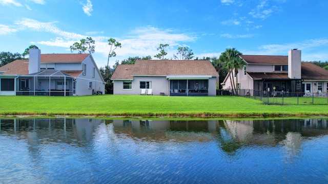 back of house featuring a lanai, a water view, and a lawn