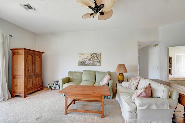 carpeted living room with ceiling fan and a textured ceiling