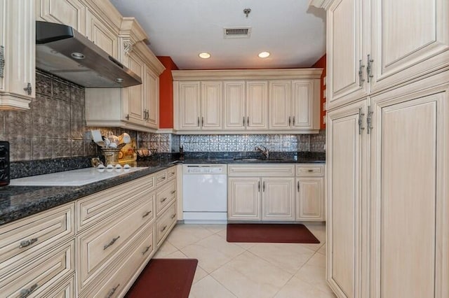 kitchen with dark stone counters, white dishwasher, decorative backsplash, light tile patterned floors, and range hood