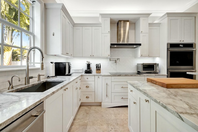 kitchen with a toaster, a sink, appliances with stainless steel finishes, wall chimney range hood, and decorative backsplash