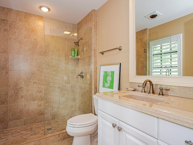 bathroom featuring vanity, toilet, and tiled shower