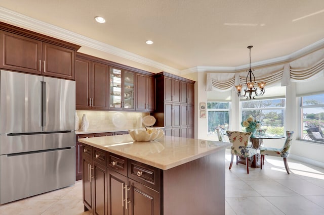 kitchen featuring backsplash, crown molding, hanging light fixtures, stainless steel fridge, and a kitchen island