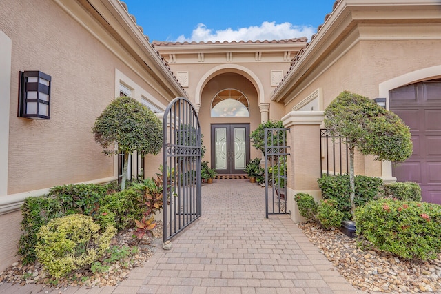 view of exterior entry featuring a garage and french doors