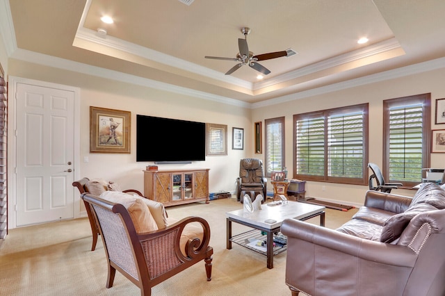 living room featuring a tray ceiling, ceiling fan, crown molding, and light colored carpet