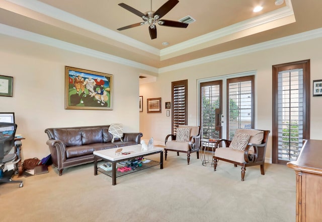 carpeted living room featuring ceiling fan, ornamental molding, and a tray ceiling