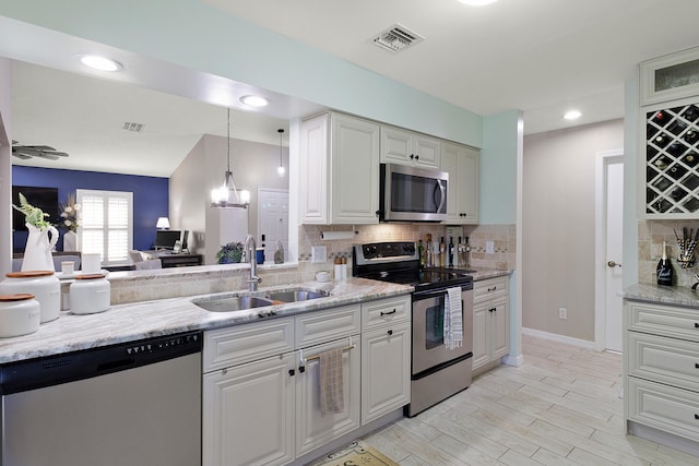 kitchen with decorative backsplash, sink, stainless steel appliances, and an inviting chandelier