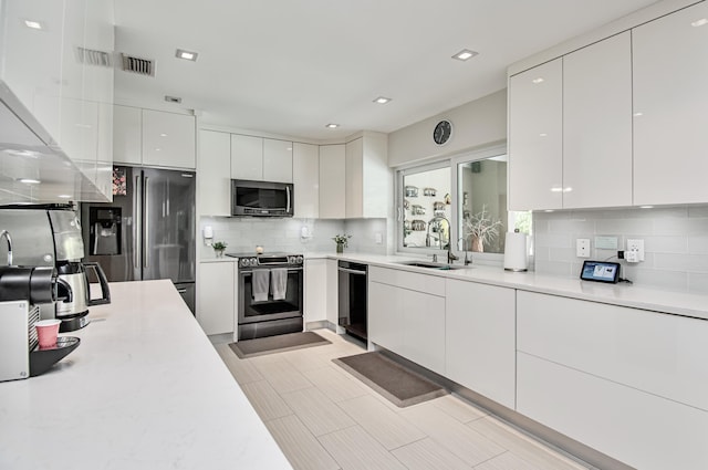 3961 NW 27th Ave, Boca Raton, FL 33434 - kitchen featuring appliances with stainless steel finishes, modern cabinets, tasteful backsplash, light countertops, and white cabinetry