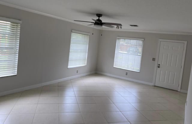 empty room with light tile patterned floors, ceiling fan, and ornamental molding