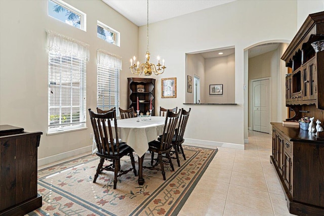 tiled dining area featuring an inviting chandelier and a towering ceiling