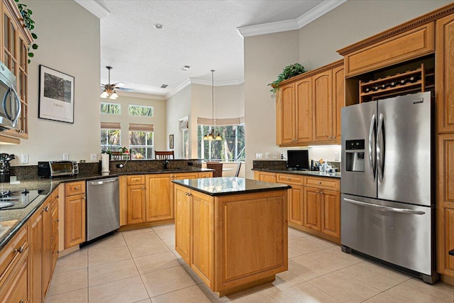 kitchen featuring appliances with stainless steel finishes, dark stone countertops, ornamental molding, light tile patterned flooring, and kitchen peninsula