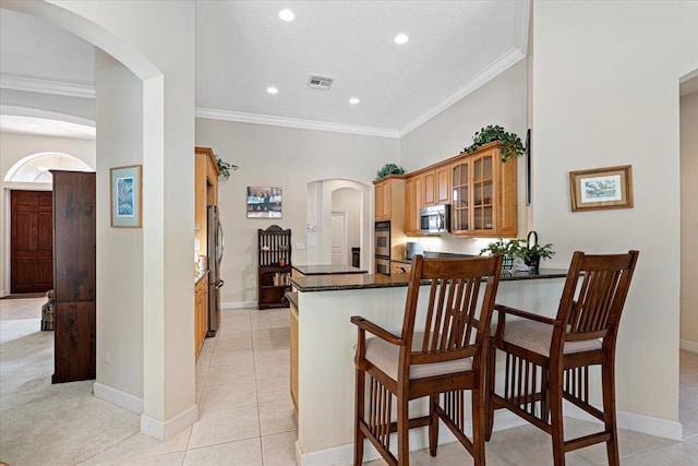 kitchen with stainless steel appliances, ornamental molding, light tile patterned flooring, and kitchen peninsula