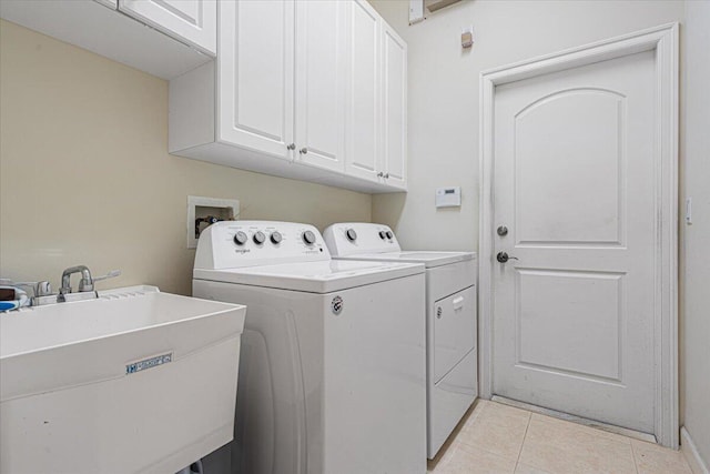 washroom featuring cabinets, light tile patterned floors, sink, and washing machine and clothes dryer