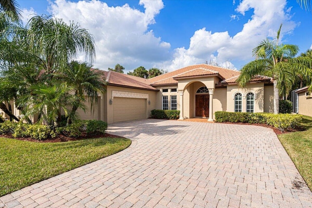 mediterranean / spanish home featuring a garage and a front lawn