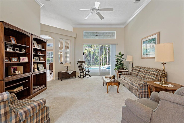 living room featuring crown molding, light carpet, ceiling fan, and a textured ceiling