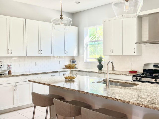 kitchen with light stone counters, sink, decorative light fixtures, white cabinets, and stainless steel range with gas stovetop