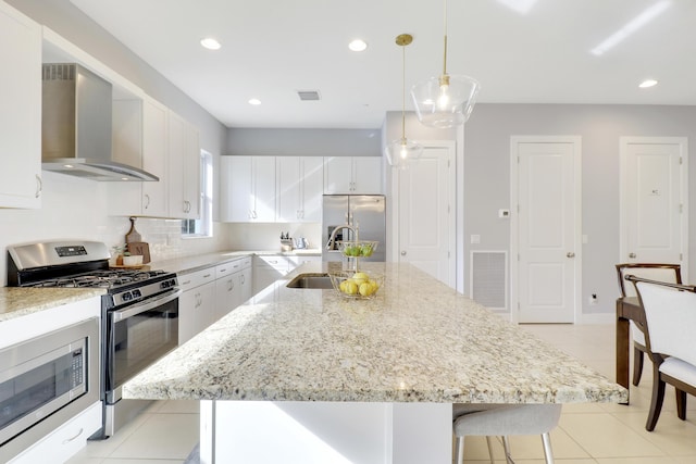 kitchen featuring a center island with sink, wall chimney exhaust hood, white cabinets, and stainless steel appliances