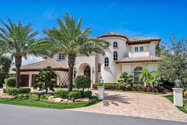 mediterranean / spanish house with a tiled roof, decorative driveway, and stucco siding