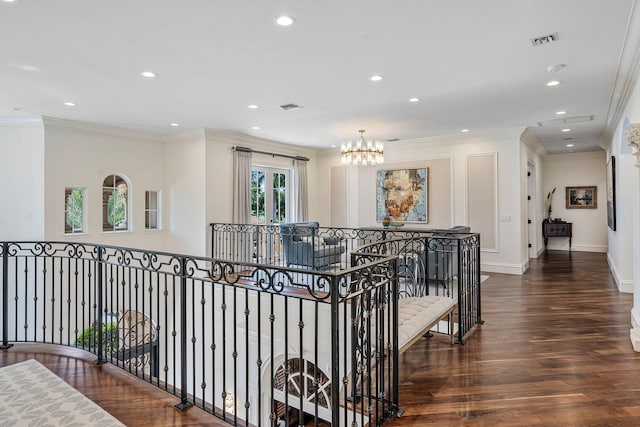 corridor with ornamental molding, visible vents, wood finished floors, an upstairs landing, and a notable chandelier