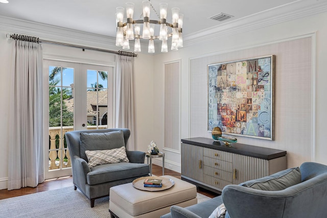 living area with ornamental molding, visible vents, a chandelier, wood finished floors, and baseboards
