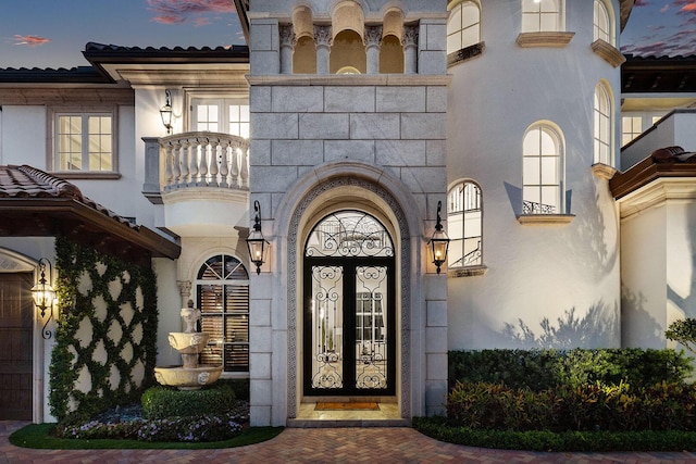 exterior entry at dusk with stucco siding and stone siding