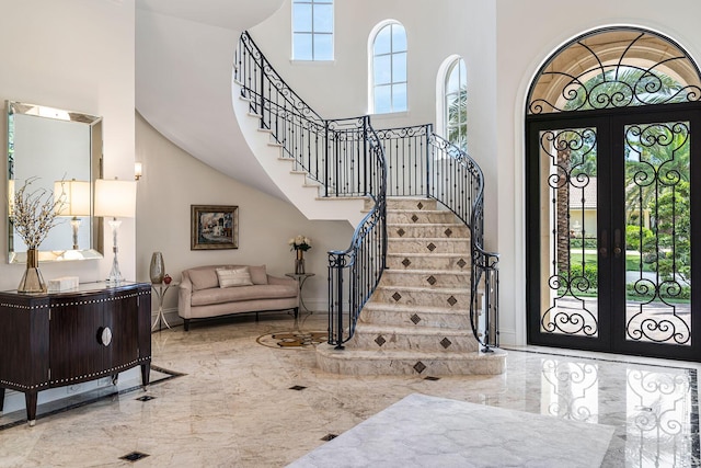 entryway with stairs, a high ceiling, marble finish floor, and french doors