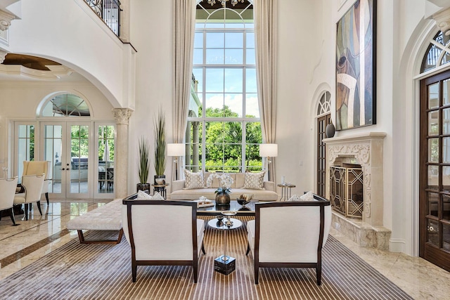 living room with arched walkways, crown molding, a towering ceiling, french doors, and a premium fireplace