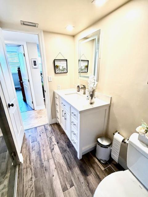 bathroom with wood-type flooring, vanity, and toilet