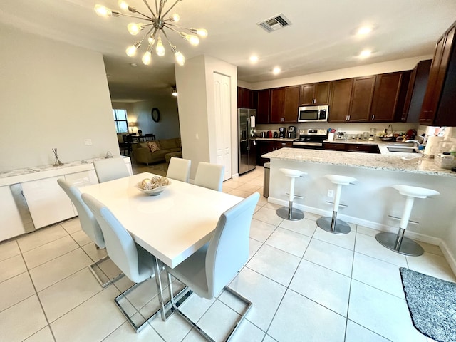 kitchen with light tile patterned floors, visible vents, stainless steel appliances, and dark brown cabinets