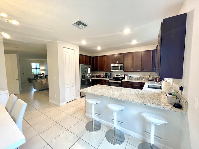 kitchen featuring light tile patterned floors, light stone counters, a sink, visible vents, and appliances with stainless steel finishes