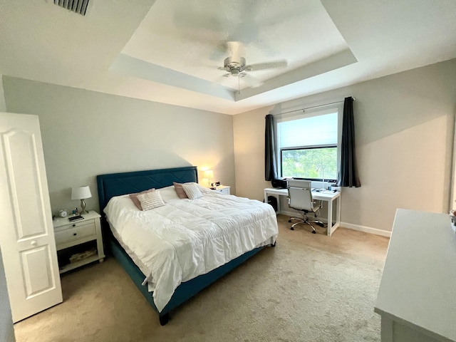 bedroom featuring light colored carpet, a ceiling fan, baseboards, visible vents, and a tray ceiling