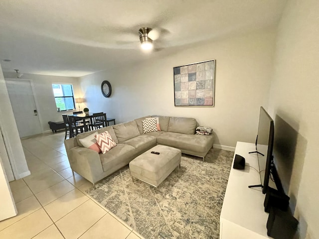 living area featuring baseboards, a ceiling fan, and light tile patterned flooring