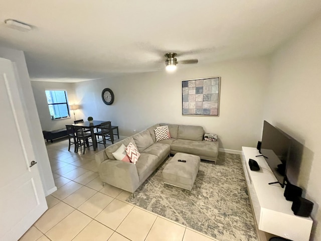 living room with light tile patterned flooring, a ceiling fan, and baseboards