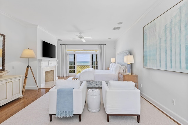 bedroom featuring ornamental molding, ceiling fan, light hardwood / wood-style flooring, a high end fireplace, and access to outside