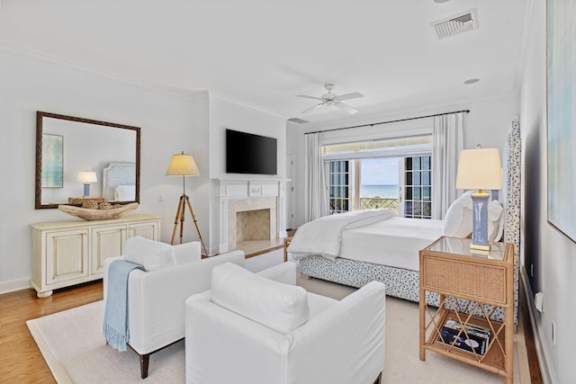 bedroom with access to exterior, a premium fireplace, ceiling fan, crown molding, and light wood-type flooring