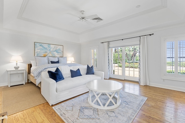 bedroom with ceiling fan, access to exterior, light hardwood / wood-style flooring, and a tray ceiling