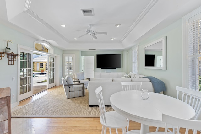 dining room with ornamental molding, light hardwood / wood-style floors, ceiling fan, and a raised ceiling