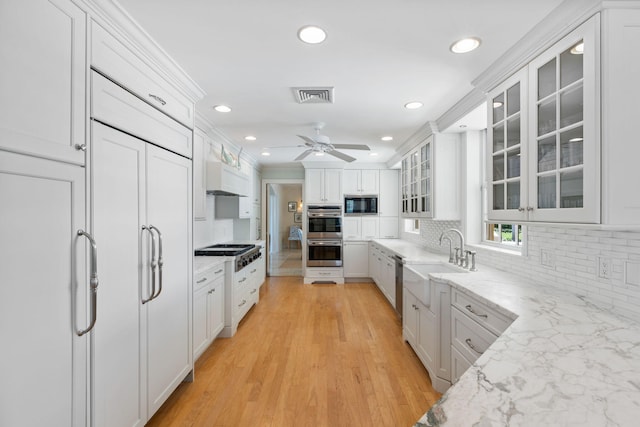 kitchen featuring sink, white cabinetry, light stone countertops, and built in appliances