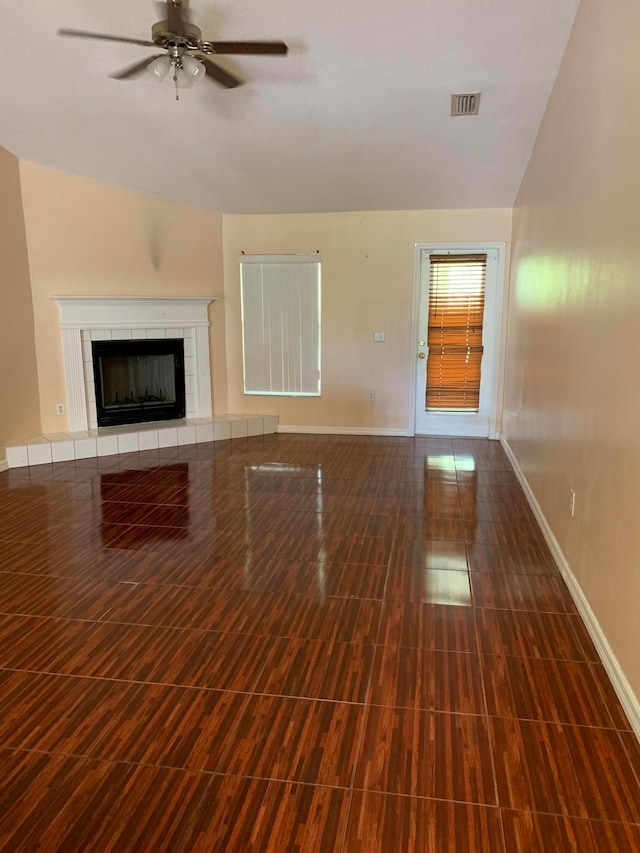 unfurnished living room featuring lofted ceiling, ceiling fan, and a tiled fireplace