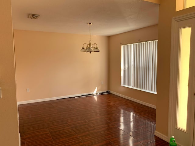 tiled empty room featuring a chandelier