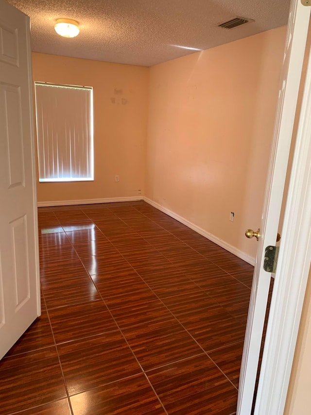 tiled spare room featuring a textured ceiling