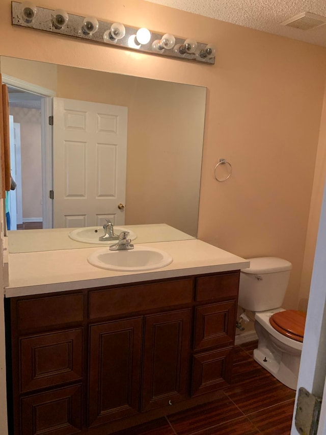 bathroom featuring toilet, a textured ceiling, and vanity